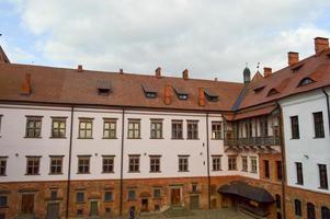 Beautiful yellow historical medieval European low-rise buildings with a red tile roof gable and rectangular windows with bars photo