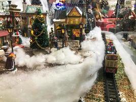 New Year's landscape. miniature for the showcase. Christmas trees are decorated for the new year with golden garlands and balls. next to a toy railway with snow-covered rails photo