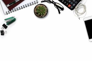 White office desk with smartphone with black screen, calculator, and supplies. Top view with copy space photo