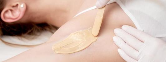 Cosmetologist applying wax paste on armpit photo