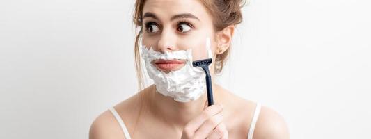 Woman shaving her face by razor photo