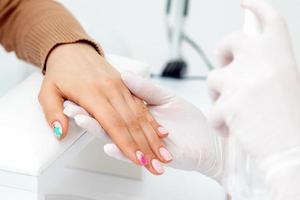 Manicure master hands spraying nails photo