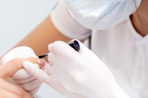 Human hands covering clear varnish on female nails photo