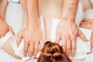 Woman receiving back massage in four hands. photo