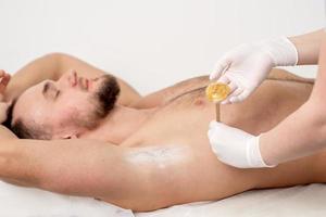 Cosmetologist applying wax paste on armpit photo