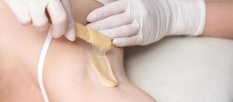 Cosmetologist applying wax paste on armpit photo