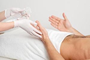 Nurse hand sanitizing hands of male patient photo