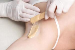 Cosmetologist applying wax paste on armpit photo