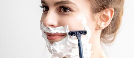 mujer afeitándose la cara con navaja foto