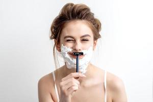 Woman shaving her face by razor photo