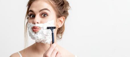 Woman shaving her face by razor photo