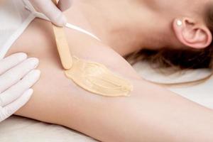 Cosmetologist applying wax paste on armpit photo