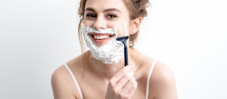 Woman shaving her face by razor photo