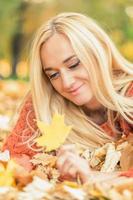 la mujer se acuesta en las hojas en el parque de otoño foto