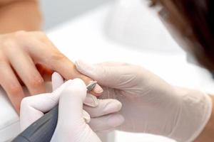 Manicure master uses an electric nail machine photo