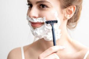 Woman shaving her face by razor photo