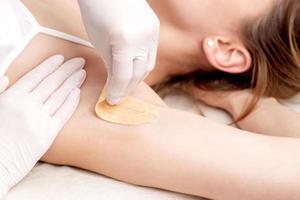 Cosmetologist applying wax paste on armpit photo