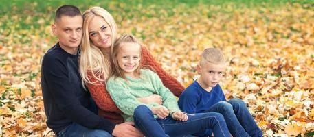 Portrait of young family sitting in autumn leaves photo