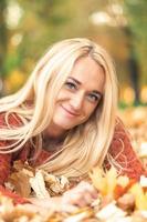 Woman lies down on leaves at the autumn park photo