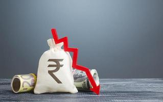 Indian rupee money bag and red arrow down. Economic difficulties. Capital flight, high risks. Costs expenses. Crisis, loss savings. Stagnation, recession, declining business activity, falling wealth. photo