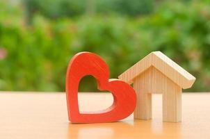 casa con un corazón de madera rojo. casa de los enamorados. vivienda asequible para familias jóvenes, programa de apoyo. hogar hospitalario de los padres. la construcción de la vivienda de tus sueños. compra y alquiler de bienes inmuebles. foto