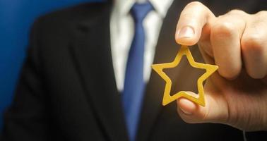 Man holds a golden star in his hand. Symbol of success and excellence. Good reputation, prestige, high recognition. Status, rating. Good ratings and reviews. VIP. Job promotion and career growth. photo