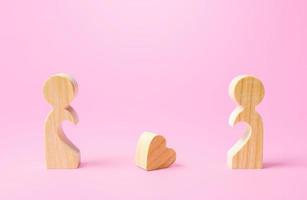 Figurines of people separated from each other and a lost heart. Breakup, end of love. Relationship problems of the couple. Take the first step towards reconciliation. Not whole without each other photo