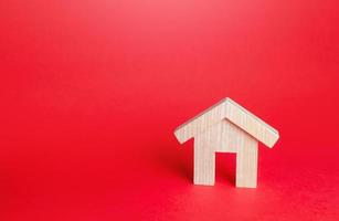 Wooden house on a red background. Buying and selling. Housing, realtor services. Mortgage loan. Construction industry, building maintenance. Renovation and home improvement. Home moving company photo