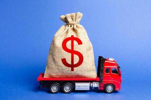 Red truck carries a big bag of money. Attracting investment in development and modernization of production and business projects. Revenue profit. super profit. corruption schemes. Financial groups photo