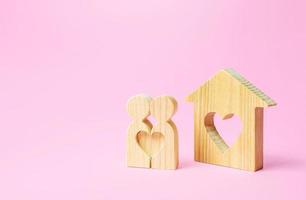 Figures of a love couple stand near house with a heart. Affordable cheap housing for young couples and newlyweds. Stimulating of appearance of new families, preferential mortgage loans, social support photo