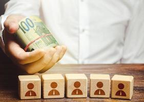 hombre de negocios con rollo de billetes de dinero en euros sobre bloques de empleados. cálculo de la utilidad de la empresa. trabajo de personal de pago, optimización de costos. contabilidad y presupuesto. inversiones y préstamos. foto