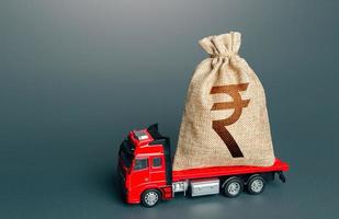 Truck with a indian rupee money bag. Loan or deposit. Financial aid, investments and subsidies. High super income. Payment of taxes. Debt load. Money transfers and transactions. Compensation. photo