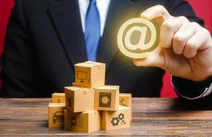 Businessman holds an email internet symbol over boxes. Sales distribution goods products online. Advertising marketing. Digitalization of customs services, reduction of bureaucratic corruption risks. photo