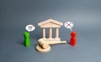 Two figures of people opponents stand near the courthouse and the judge's gavel. Conflict resolution in court, claimant and respondent. Court case. the defendant defends the position of innocence. photo