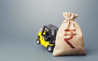 A forklift cannot lift a Indian rupee money bag. Stimulating economy. Strongest financial assistance, support of business and people. Interest rate. Helicopter money, subsidies soft loans. photo