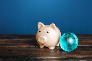 Piggy bank and blue earth globe. World financial system. Payment services, international money transfers. financial flows. Protection of savings from inflationary risks. Investments in other countries photo