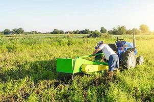 un agricultor sirve un tractor en un campo de plantaciones agrícolas. reparación de la máquina de excavación de patatas. mantenimiento de equipos y maquinas. avería inesperada durante el trabajo de cosecha. servicio de tractores. foto