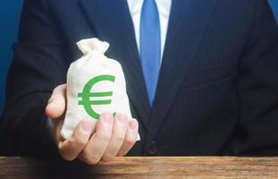 Man holds euro money bag. Granting financing business project or education. Provision cash financial credit. Profits dividends. Donations and philanthropy. Social assistance. Investment. Award photo