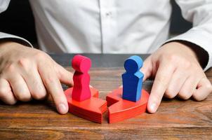 A psychologist connects the two halves of a broken heart with figures of a man and a woman standing on them. Psychological assistance in reconciliation and improving of relations between spouses. photo