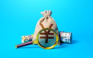 Chinese yuan or japanese yen money bag and magnifying glass. Investigating capital origins. Anti money laundering, tax evasion. Deposit or loan terms conditions. Find investment funds for business photo