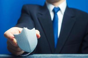 A man holds a protection shield in his hand. Safety, life and property insurance. Security personnel, maintaining law and order. Lawyer defends the rights and innocence. Protectionism, defense photo