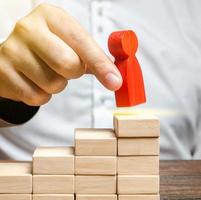 A man puts a red human figure on top of the stairs. Career growth, improvement of skills. Promotion at work of employees to leading post. The concept of success. Training. Education, business photo