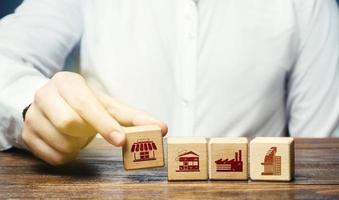 A man lays in a row blocks with symbols of business shops, offices and factories. Building a successful business empire. Investments. Merge small competitors, expansion. Franchise concept. photo