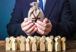 Businessman holds out a chinese yuan or japanese yen money bag to the crowd. Financial support. Tax collection. Compensation payments. Share profit. Providing money, paying salaries and grants. photo