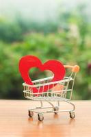 Red wooden heart in the trading cart. concept of buying love. nature background. Health care and purchase of medicines. Health care budget. Love for shopping. Favorite store. Buy love and happiness. photo