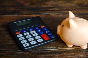 The piggy bank looks at the tax calculator. Real estate tax. Taxation on purchase or sale. Fees and duties. Annual taxes relief. Accounting and audit. Saving. Payment deferment. photo