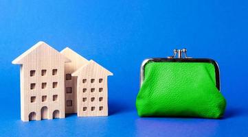 Figures of residential buildings near a large green wallet. concept of the cost of maintaining the building and utility bills. Modernization of housing, improving energy efficiency. Saving to buy home