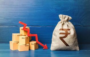 Indian rupee money bag with boxes and down arrow. Income decrease, slowdown and decline of economy. Low sales. Production decline. Reduced prices. Bad consumer sentiment and demand for goods. photo