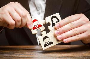 A businessman collects puzzles symbolizing a team of employees. The concept of the organization of the team and the business hierarchy. Management. The appointment of the head. Dismissal employee. photo