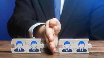 A man divides puzzle team of employees. Team split, structural fragmentation into small units. Improving company efficiency. Staff dismissal reduction. Distribution group members to parallel projects. photo